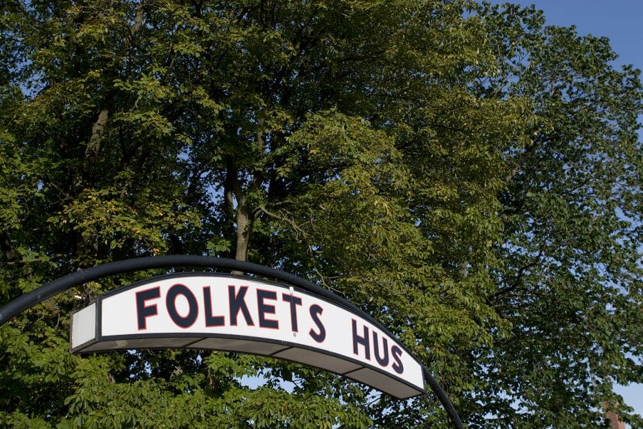 Entréskylt "Folkets hus" i naturmiljö.
